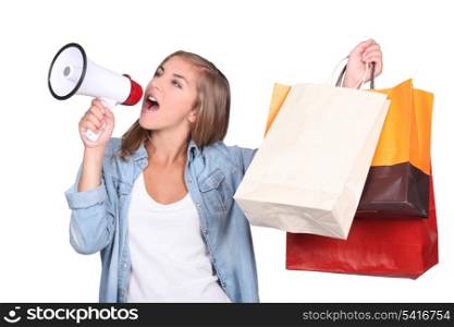 Studio shot of woman shouting into a megaphone and holding up store bags