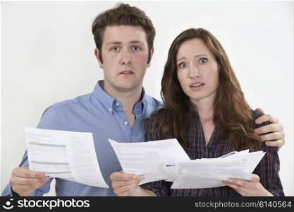 Studio Shot Of Worried Couple Looking At Bills