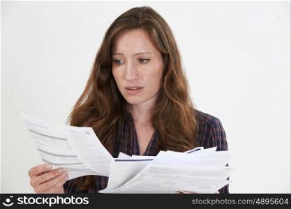 Studio Shot Of Worried Woman Looking At Bills