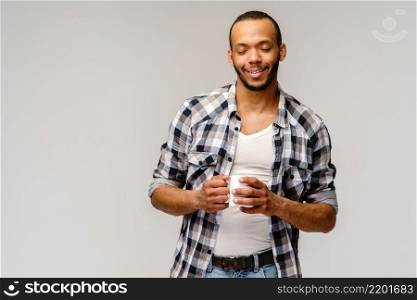 Studio shot of young african american Man having a cup of coffee over light grey background.. Studio shot of young african american Man having a cup of coffee over light grey background