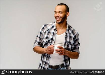 Studio shot of young african american Man having a cup of coffee over light grey background.. Studio shot of young african american Man having a cup of coffee over light grey background