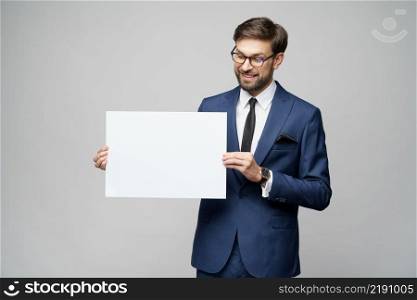 Studio shot of Young businessman holding blank signs over grey background. Young businessman holding blank signs over grey background