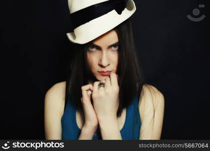 Studio shoulder portrait of young blue-eyed girl in white hat on black background