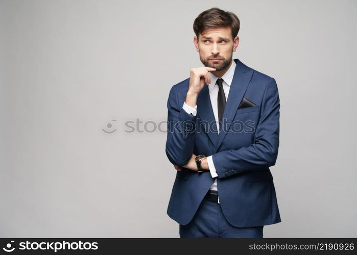 Studuo shot of thinking businessman wearing suit over grey background. Studuo shot of thinking businessman wearing suit