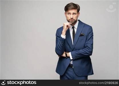 Studuo shot of thinking businessman wearing suit over grey background. Studuo shot of thinking businessman wearing suit