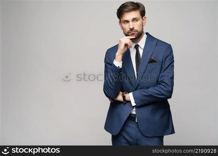 Studuo shot of thinking businessman wearing suit over grey background. Studuo shot of thinking businessman wearing suit
