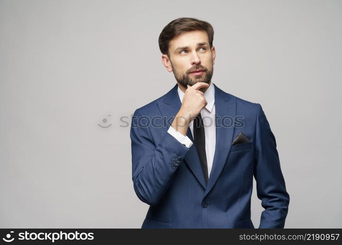 Studuo shot of thinking businessman wearing suit over grey background. Studuo shot of thinking businessman wearing suit