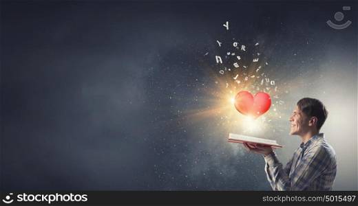 Study affair science. Young man with opened book in hands and red heart on pages