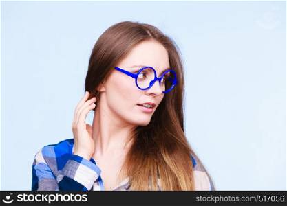 Studying, beauty of education and fun concept. Attractive nerdy woman in weird big glasses. Studio shot on blue background. Attractive nerdy woman in weird glasses