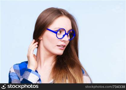 Studying, beauty of education and fun concept. Attractive nerdy woman in weird big glasses. Studio shot on blue background. Attractive nerdy woman in weird glasses