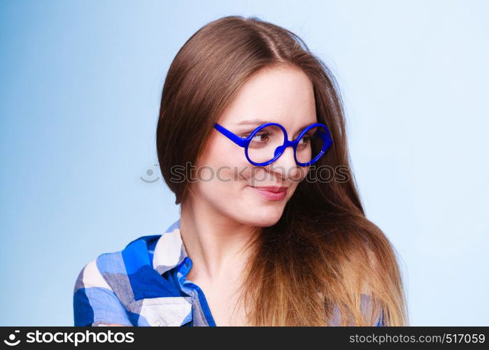 Studying, education and fun concept. Happy smiling nerdy woman in weird big glasses. Studio shot on blue background. Happy smiling nerdy woman in weird glasses