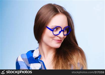 Studying, education and fun concept. Happy smiling nerdy woman in weird big glasses. Studio shot on blue background. Happy smiling nerdy woman in weird glasses