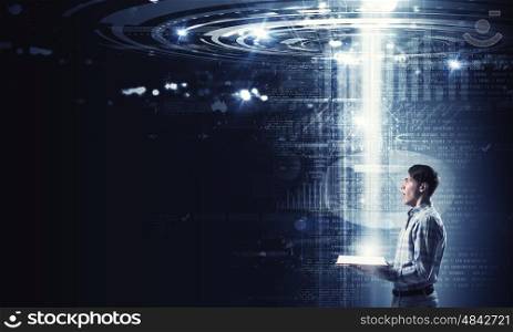 Studying media technologies. Young man with book in hands on digital background