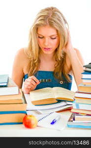 Studying teen girl sitting at table and reading book&#xA;