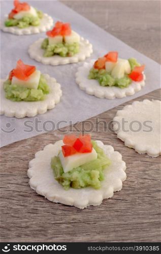 Stuffed avocado with cheese and tomato on a slice of puff pastry