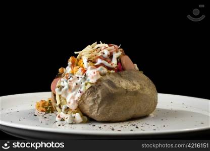 Stuffed baked potato on plate isolated on black background
