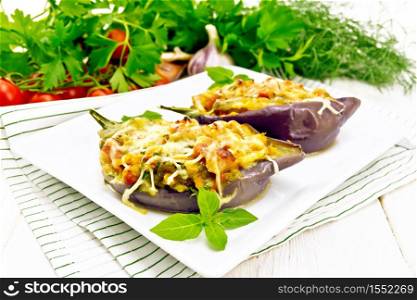 Stuffed eggplant with smoked brisket, tomatoes, onions, carrots with garlic, cheese and herbs in a plate on a napkin on white wooden board background