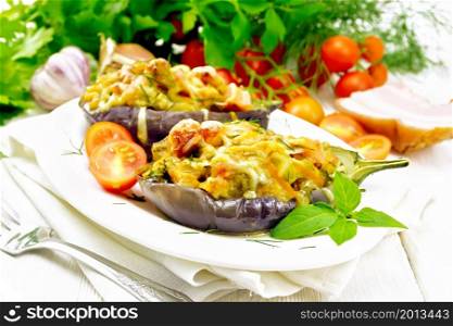 Stuffed eggplant with smoked brisket, tomatoes, onions, carrots with garlic, cheese and herbs in an oval plate on a kitchen towel on white wooden board background