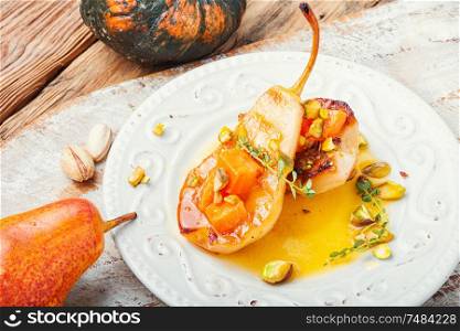 Stuffed pear pumpkin and pistachio.Autumn food.Baked pears with syrup on plate. Ripe baked pear with pumpkin