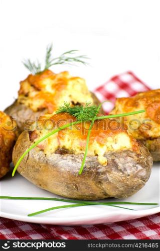 stuffed potatoes covered with cheddar cheese decorated with chives and dill leaves in a white plate