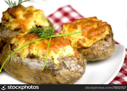 stuffed potatoes covered with cheddar cheese decorated with chives and dill leaves in a white plate