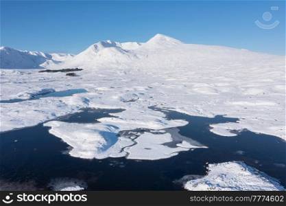 Stunning aerial drone Winter landscape images of Loch Ba and snow covered mountains in background in Scottish Highlands