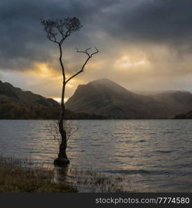 Stunning Autumn sunrise landscape image of Buttermere in Lake District with dramatic stormy sky