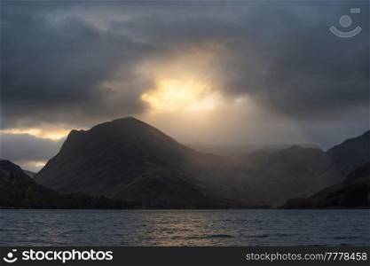 Stunning Autumn sunrise landscape image of Buttermere in Lake District with dramatic stormy sky