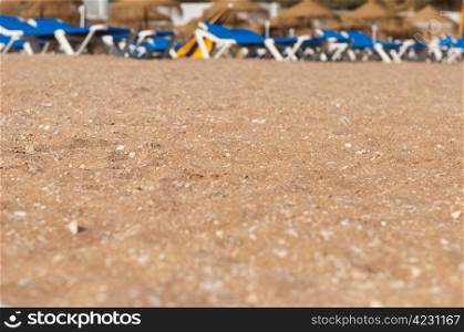 stunning beach sand with small shells on a very shallow DOF (plenty copy-space for your design, chairs and umbrellas at the background)