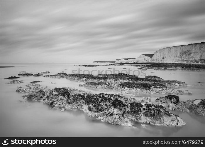 Stunning black and white long exposure landscape image of low ti. Beautiful black and white long exposure landscape image of low tide beach with rocks at sunrise