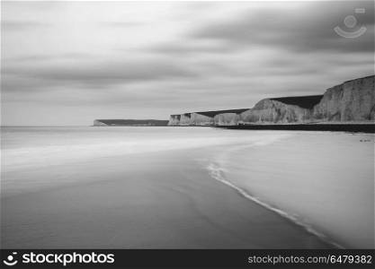 Stunning black and white long exposure landscape image of low ti. Beautiful black and white long exposure landscape image of low tide beach with rocks at sunrise