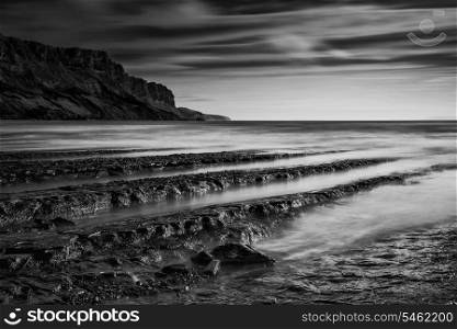 Stunning black and white seascape coastline and rocky shore at sunset
