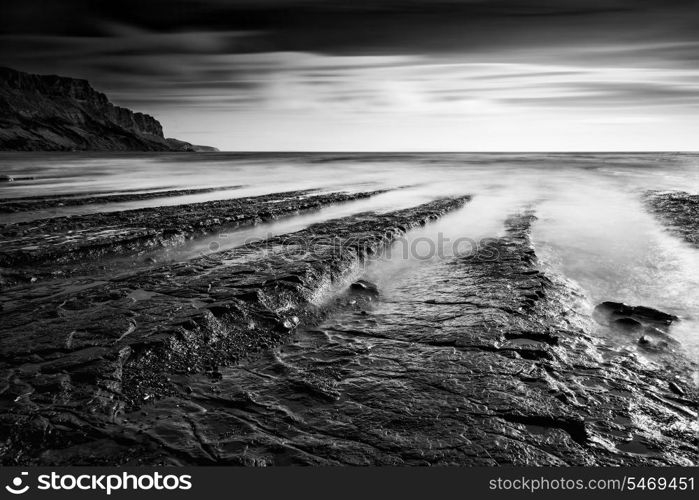 Stunning black and white seascape coastline and rocky shore at sunset