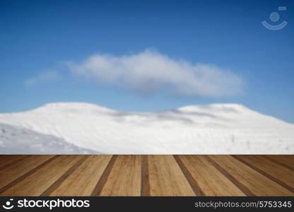 Stunning blue sky mountain landscape in Winter with snow covered slopes with wooden planks floor