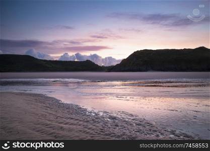 Stunning colorful Summer sunrise landscape image of Three Cliffs Bay in South Wales
