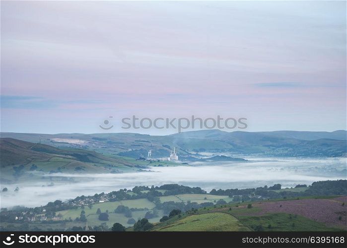 Stunning dawn sunrise landscape image from Higger Tor towards Hope Valley layered in fog in Summer in Peak District England