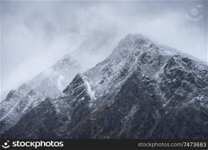 Stunning detail landscape images of snowcapped Pen Yr Ole Wen mountain in Snowdonia during dramatic Winter storm