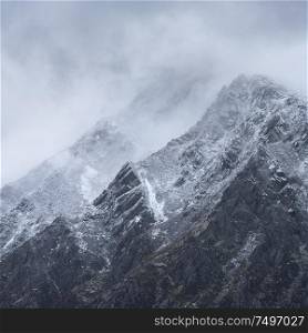 Stunning detail landscape images of snowcapped Pen Yr Ole Wen mountain in Snowdonia during dramatic Winter storm