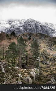 Stunning dramatic landscape images of Ogwen Valley in Snowdonia during Winter with snowcapped Glyers mountain range in the background