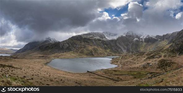 Stunning dramatic Winter landscape image of Llyn Idwal and snowcapped Glyders Mountain Range in Snowdonia