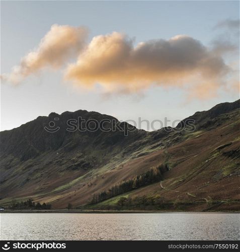 Stunning epic Autumn Fall landscape Buttermere in Lake District with beautiful early morning sunlight playing across the hills and mountains