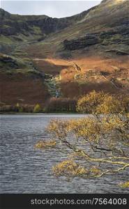 Stunning epic Autumn Fall landscape Buttermere in Lake District with beautiful early morning sunlight playing across the hills and mountains
