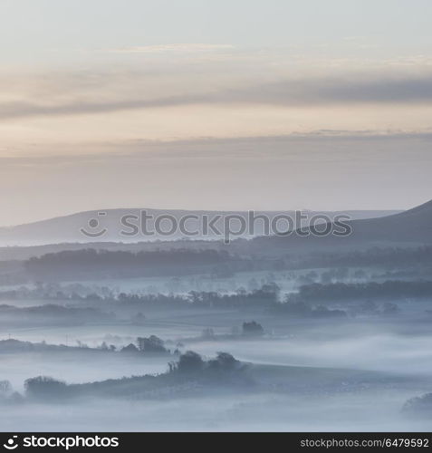 Stunning foggy English rural landscape at sunrise in Winter with. Beautiful foggy English countryside landscape at sunrise in Winter with layers rolling through the fields