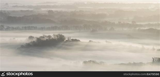 Stunning foggy English rural landscape at sunrise in Winter with. Beautiful foggy English countryside landscape at sunrise in Winter with layers rolling through the fields