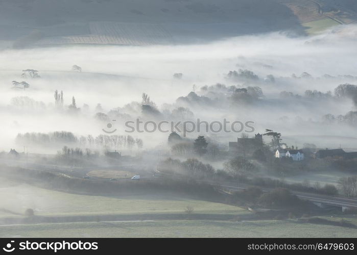 Stunning foggy English rural landscape at sunrise in Winter with. Beautiful foggy English countryside landscape at sunrise in Winter with layers rolling through the fields