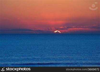 Stunning image of deep sunset over calm smooth sea with vibrant colors and plenty of copy space