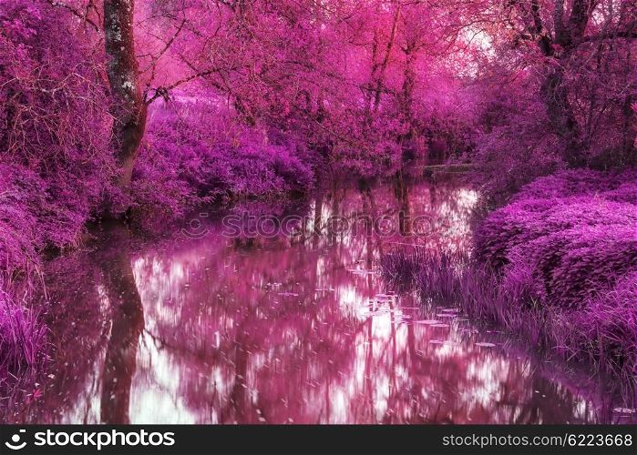 Stunning infra red alternative color landscape image of trees over river