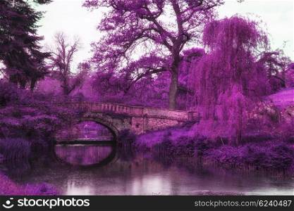 Stunning infra red landscape image of old bridge over river in countryside