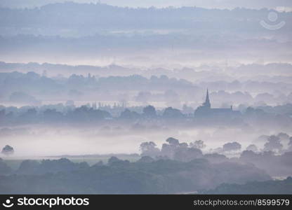 Stunning landscape image of layers of mist rolling over South Downs National Park English countryside during misty Summer sunrise