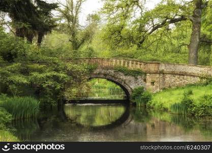Stunning landscape image of old medieval bridge over river with mirror like reflections